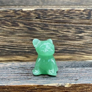 Macro shot of 3cm green semi-precious stone french bulldog carving on wooden surface