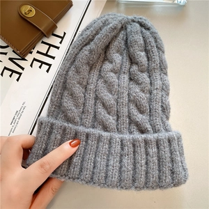 Detailed macro view of the grey chunky knit cable pattern on a warm winter beanie hat