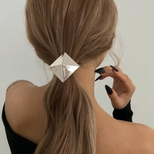 Detail of silver geometric diamond-shaped metal hair cuff on a ponytail hairstyle