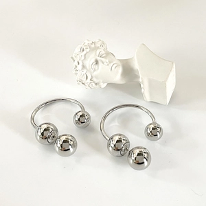 Macro detail of silver horseshoe earrings with metallic beads on polished surface