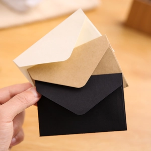 Mini vintage kraft paper envelopes in white, brown, and black held in hand