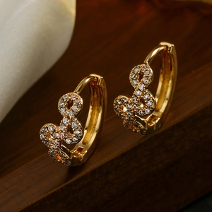 Gold plated infinity hoop earrings with clear cubic zirconia on a dark wood background
