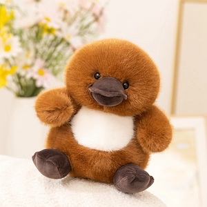 Close-up of soft brown plush platypus toy with realistic duck bill on a white textured surface