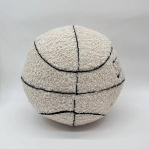 Detail of off-white plush basketball pillow showing soft textured fabric and black stitching