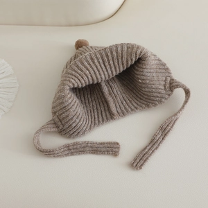 Vue détaillée du tricot côtelé d'un bonnet à oreillettes pour bébé marron avec pompon