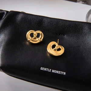 Macro shot of 18K gold plated pretzel twist earrings on a black leather background