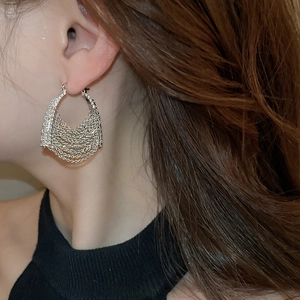 Close-up of silver tassel earrings with multiple fine chains and zircon bag design