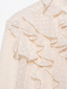Detailed view of beige chiffon blouse featuring ruffle trim and textured polka dots fabric