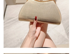 Close-up of golden glitter shell clutch bag with metallic frame held by a hand