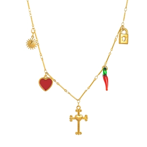 Détail d'un collier en acier doré avec pendentifs soleil, cœur, croix et piment
