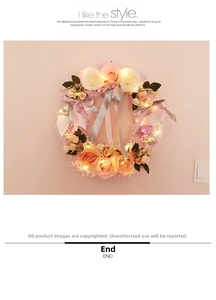 Close-up of pink and white roses wreath with warm LED lights and silk ribbons