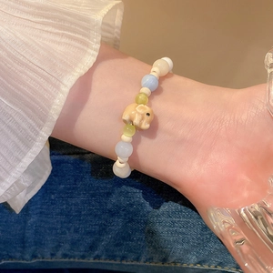 Détail du bracelet en perles pastel avec un éléphant jaune et des pierres œil de chat
