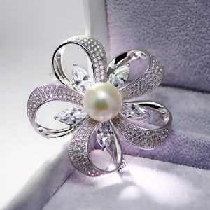Vue macro d'une broche fleur argentée avec perle blanche et zircons micro-pavés