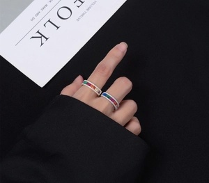 Detail of gold and silver rainbow eternity rings with colored zircon stones on hand
