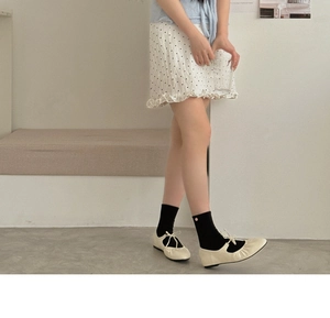 Close-up of pink crew socks styled with cream Mary Jane ballet flats and bow detail