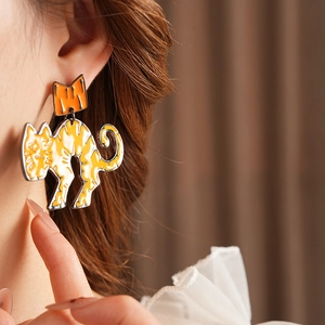 Close-up of cute orange cartoon cat earrings with bow detail on a female model