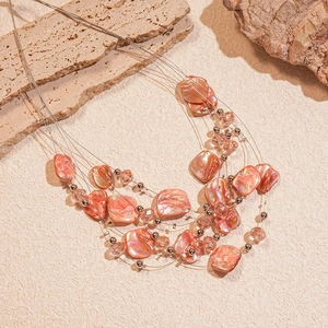 Detail of multilayer crystal beaded necklace with iridescent peach shell charms on stones