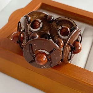 Macro view of wide geometric coconut shell and wood bead stretch bracelet on a wooden tray
