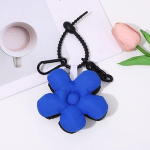 Blue puffy flower keychain with black metal clip on a desk with coffee and tulip