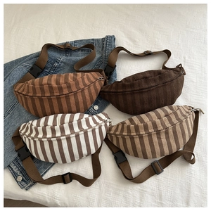 Flat lay of four corduroy fanny packs in solid and striped patterns with wide straps