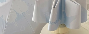 Detail of light blue sun umbrella showing butterfly print and waterproof fabric texture