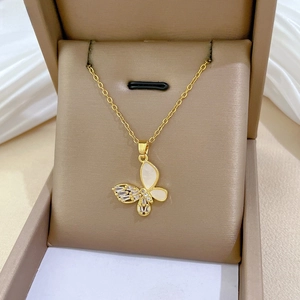 Macro detail of gold butterfly pendant with shell inlay and cubic zirconia on silk