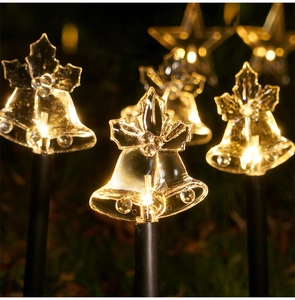Macro shot of solar Christmas garden stakes with LED bell and star shapes glowing warmly