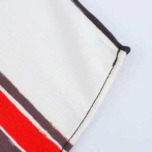 Macro detail of red and brown striped asymmetric fabric with fine twill weave and neat hem