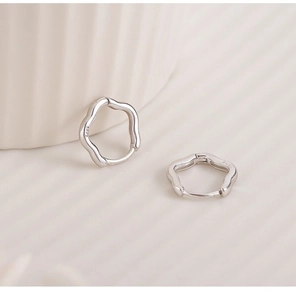 Detailed close-up of wavy S925 sterling silver hoop earrings on a textured background