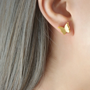 Frosted butterfly stud earrings in rose gold finish shown on model's earlobe