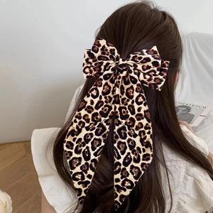Rear view of model wearing a large leopard print bow hair clip in a cozy indoor setting