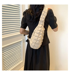 Gros plan sur un sac bandoulière matelassé beige au design nuage porté par un mannequin
