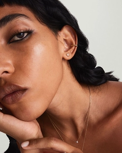 Close-up of model wearing gold heart stud earrings and textured ear cuff set