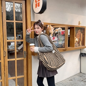 Brown plush tote bag with black stripes shown in a lifestyle street photography setting