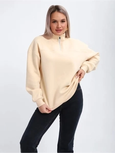 Detail of half-zip pullover collar with metallic zipper on apricot fleece sweatshirt