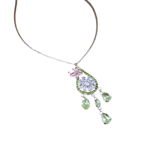 Collana floreale in argento con zirconi verdi e rosa e nappe su sfondo bianco puro