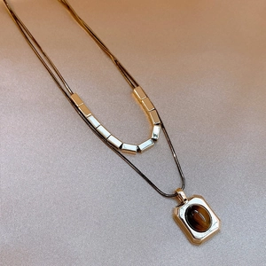 Macro shot of double-layer gold plated necklace with tiger eye pendant on silk background