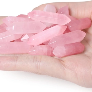 Multiple pink rose quartz double-pointed hexagonal crystal wands held in hand