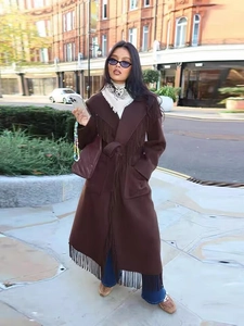 Detail of a brown wool coat featuring elegant fringe hem and a waist belt in street style