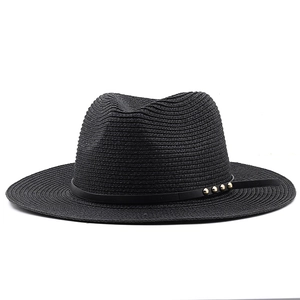 Detail of black straw fedora hat featuring a leather band with three gold studs