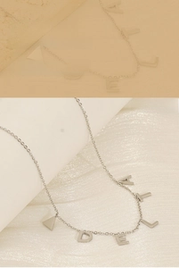 Détail d'un collier en acier titane argenté avec divers pendentifs lettres et un triangle