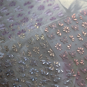 Macro detail of gold and silver metallic butterfly and floral nail art stickers