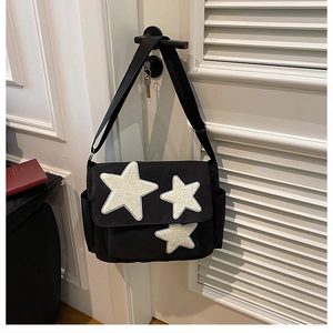 Detail of black crossbody bag with white plush stars hanging on a shutter door handle