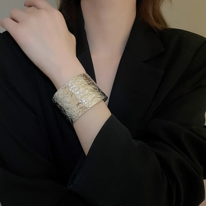 Close-up of a wide silver cuff bracelet with hammered texture on a model's wrist