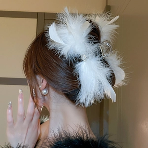 Detailed side view of a large white feather hair claw clip worn on a soft hair bun