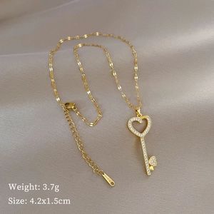 Gold heart-shaped key pendant necklace with crystals on silk background