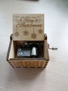Detail shot of wooden music box with laser engraved Merry Christmas text and movement
