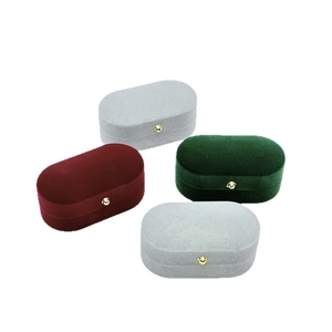 Oval velvet jewelry boxes with gold clasps in grey, burgundy, and dark green colors