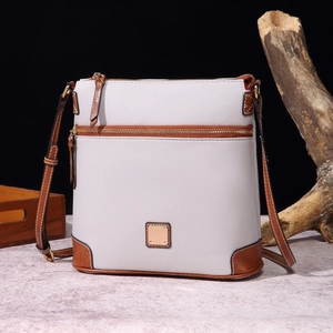 Detail of white pebble grain leather crossbody bag with brown trim and front zipper pocket