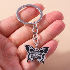 Detailed close-up of a gothic butterfly skull keychain with black and white enamel